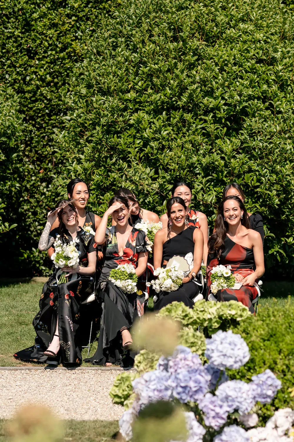 Bridesmaids In Black Dresses Holding White Bouquets Outdoors