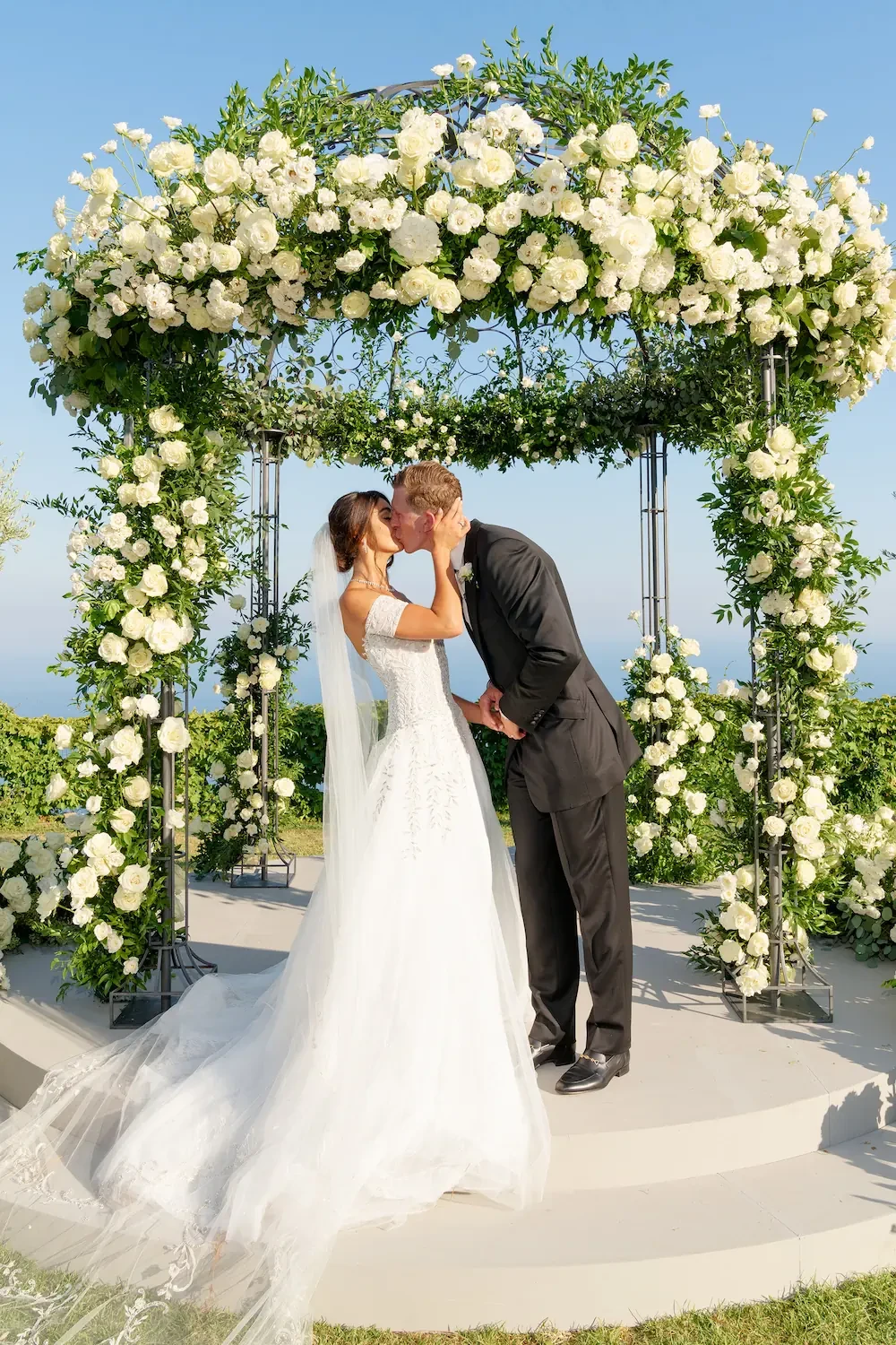 Bride and Groom kissing under the wedding arch