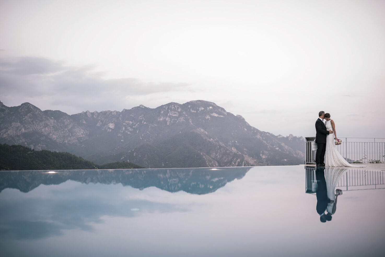 Bride and groom by the pool of Caruso Hotel